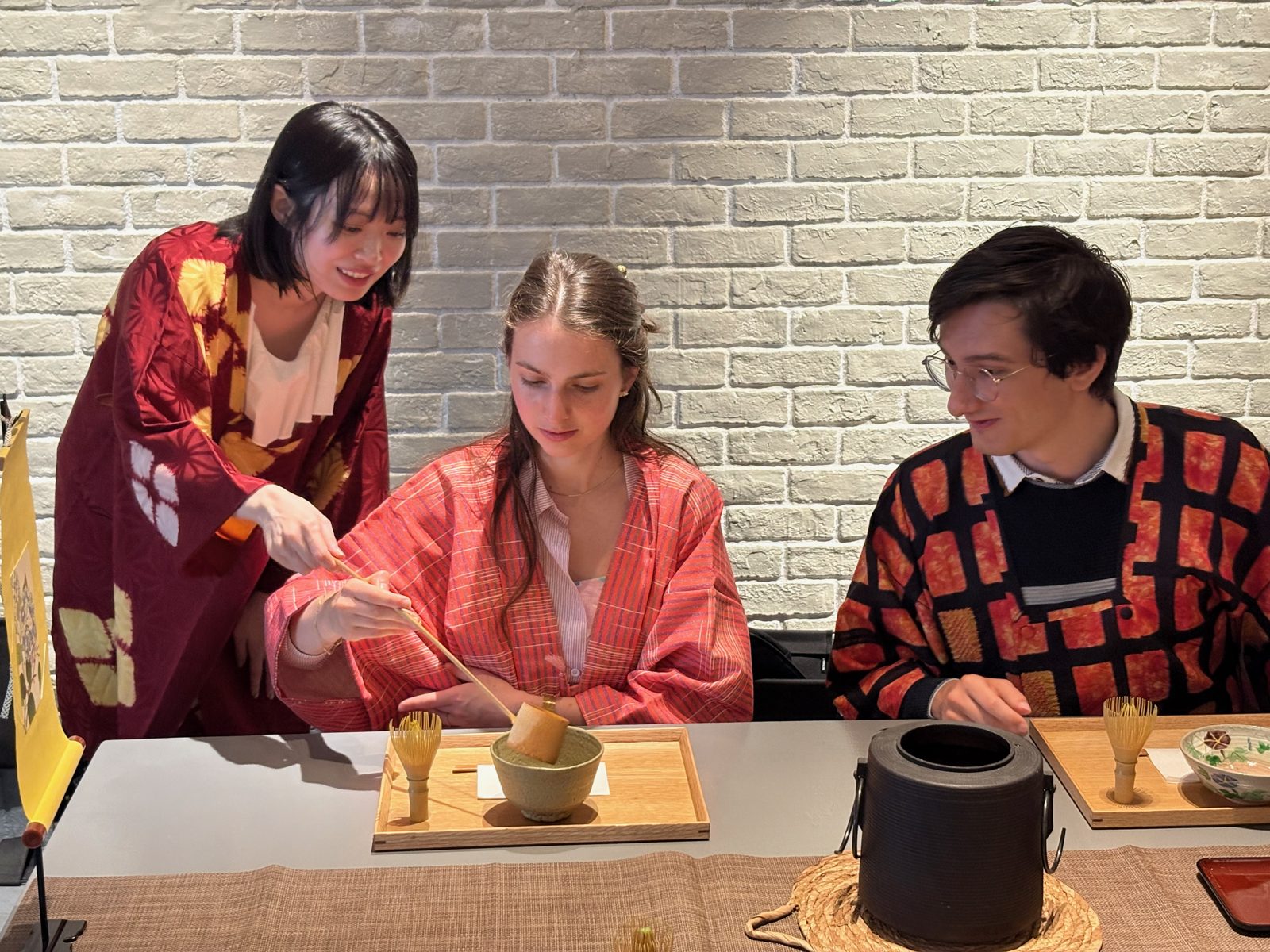 The Urasenke tea master guiding a guest as she scoops matcha into her bowl