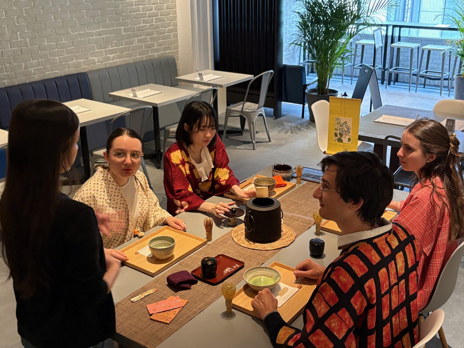 The tea ceremony table with iron kettle, scroll, and bowls of matcha
